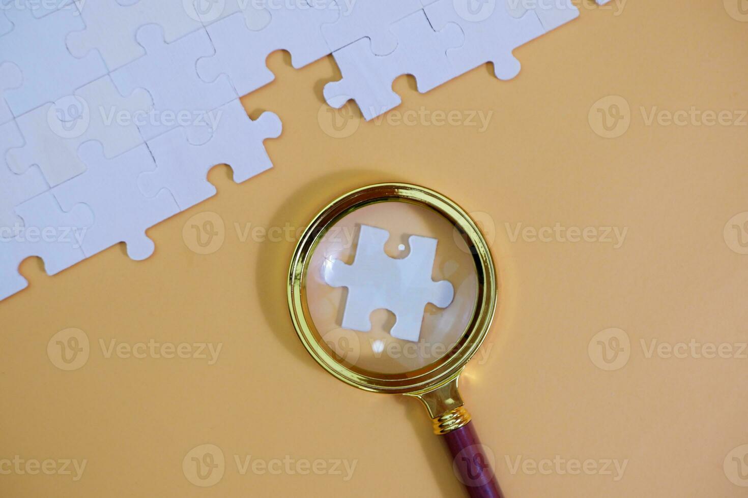 magnifying glass and on the missing puzzle piece. photo illustration concept of searching for and recruiting new employees