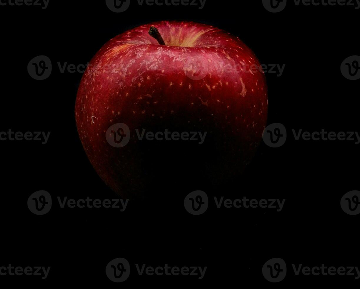 bright, vividly colored red apple on a black background during a studio photo session in the winter of 2023