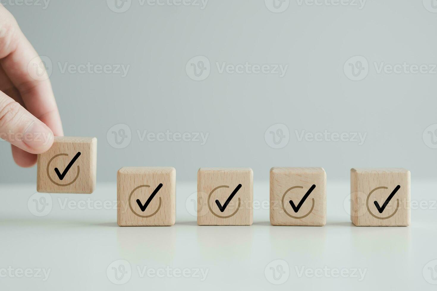 Checklist, To do list, Task list, Survey and assessment. Quality Control. Goals achievement and business success. Hand holding Check mark icon on wooden blocks to complete check list. photo