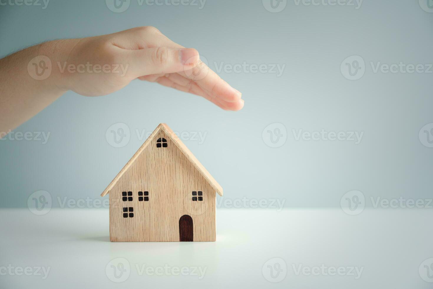 Protect house. Insurance concept. Hand protection house model that symbolize the coverage from risk disaster and problem. Protection assets or family from event of damages. photo