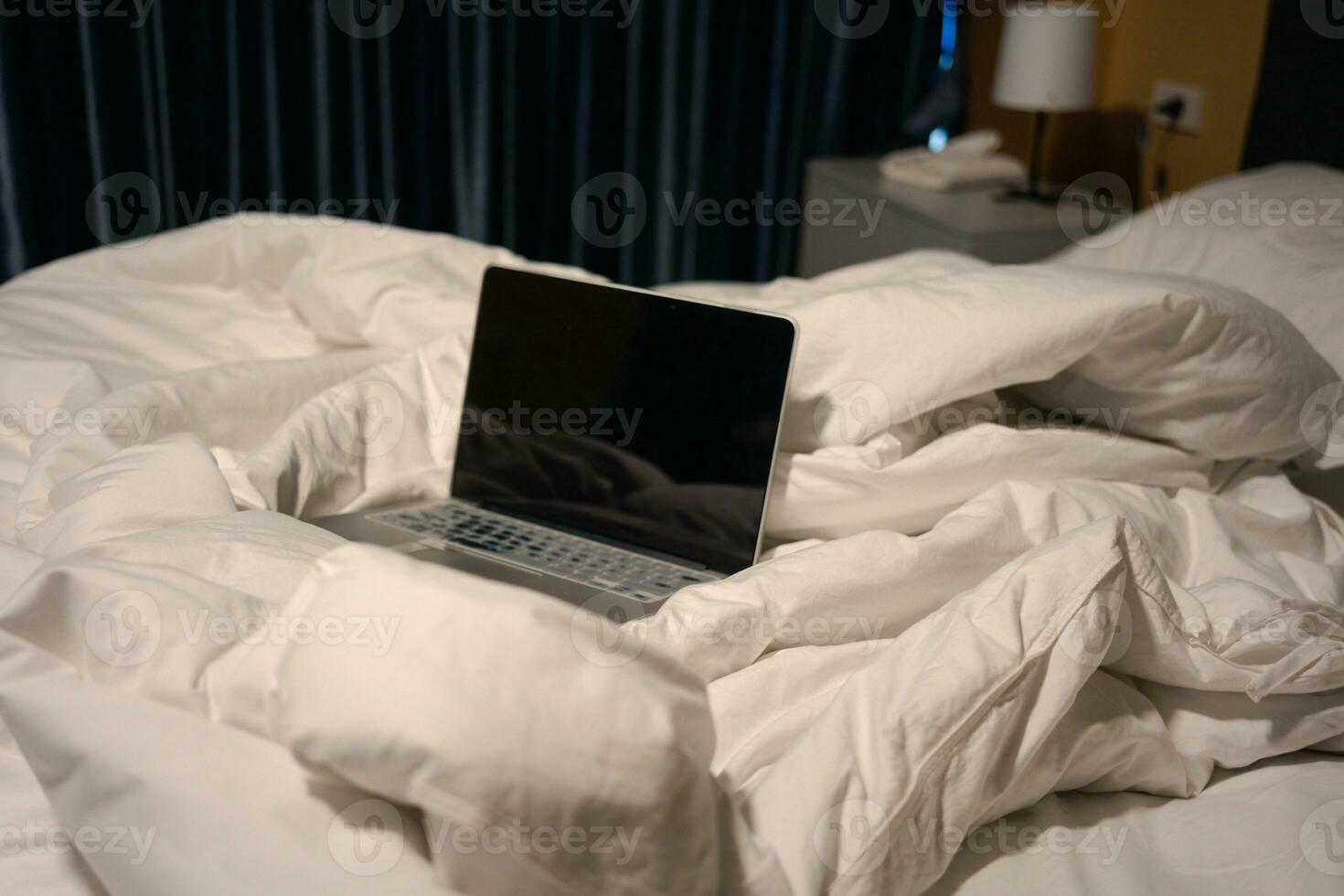 Laptop on white bed in the bedroom. photo