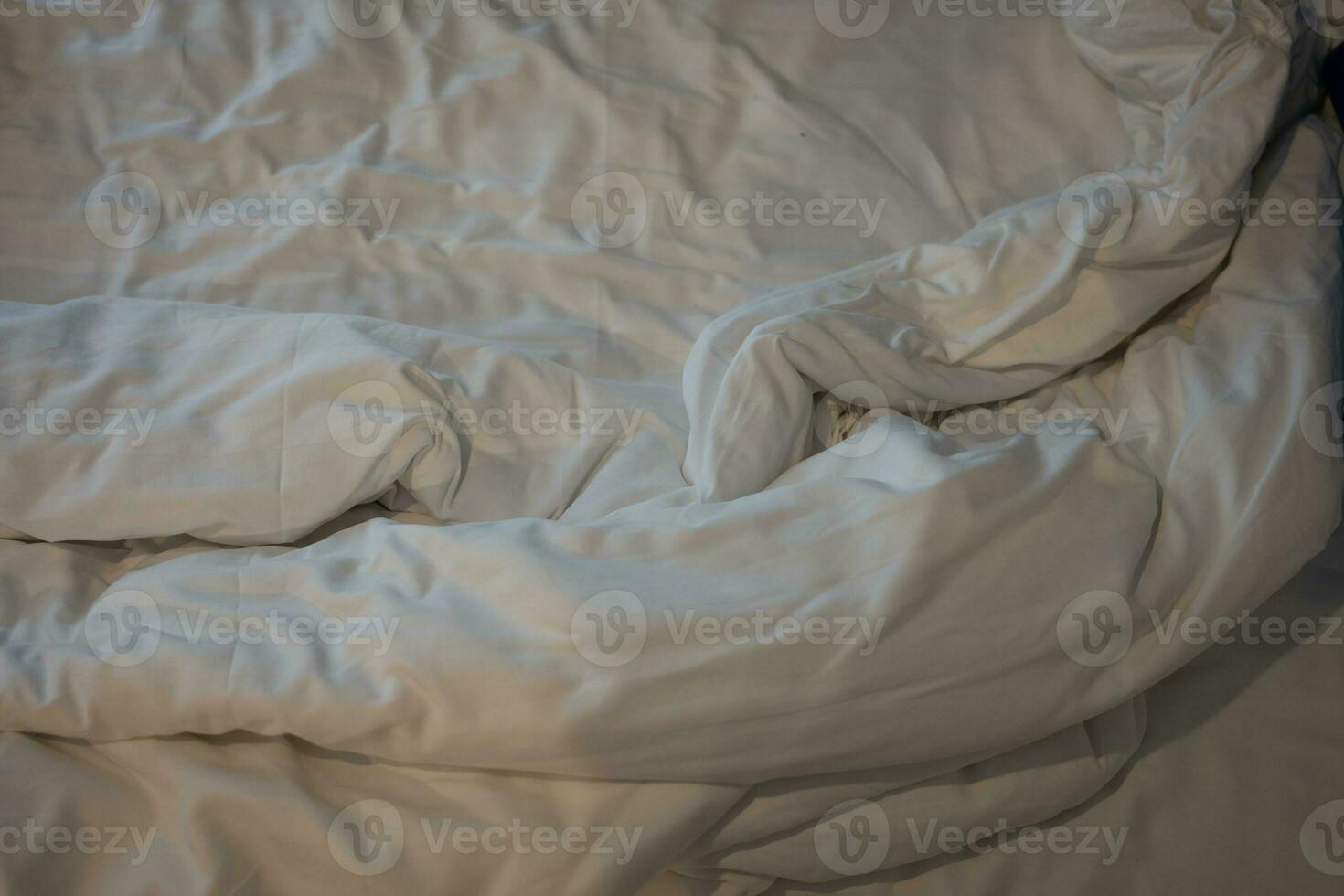 Unmade white bedding sheets and pillow, Messy bed after night sleep concept. photo