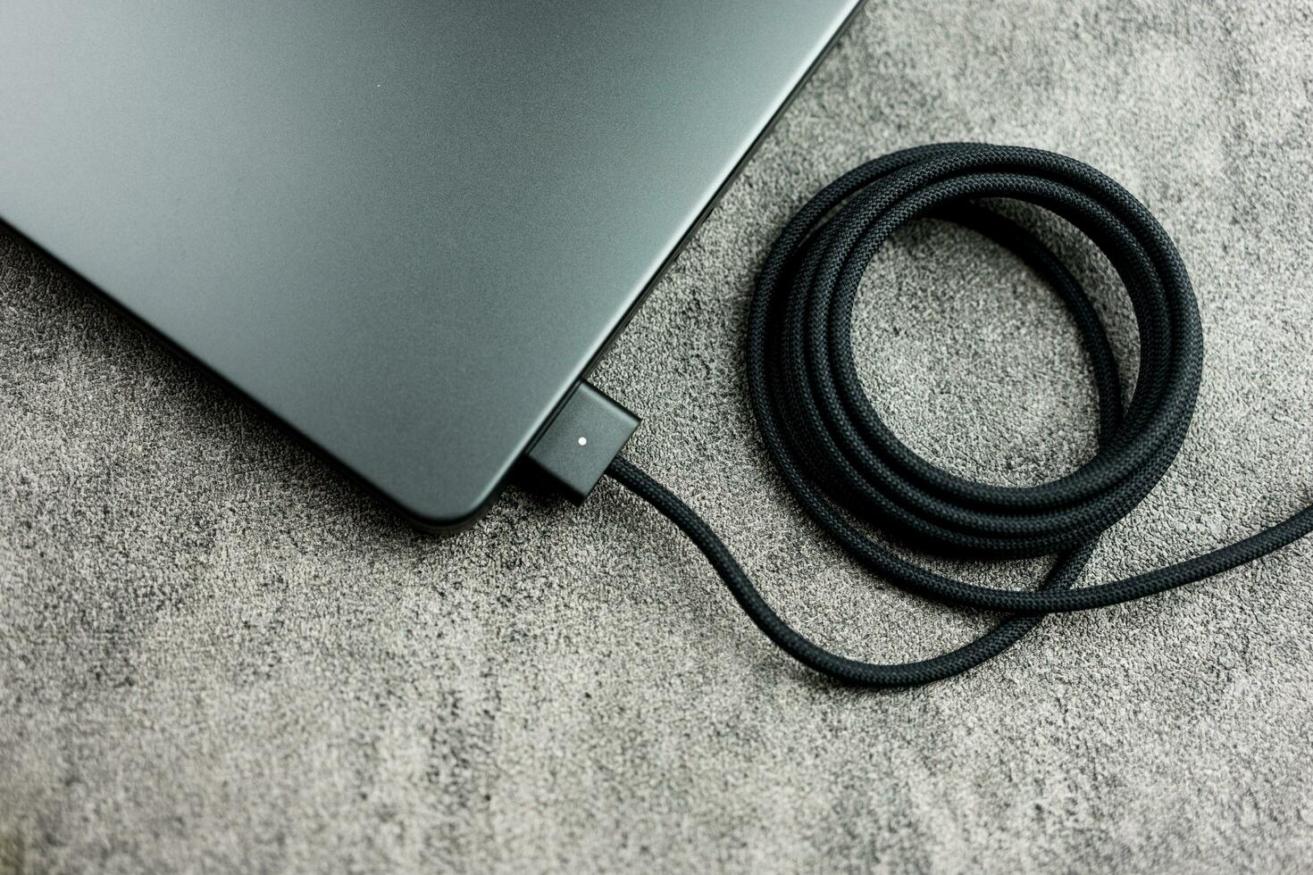 Bangkok, Thailand - December 27, 2023 A black braided USB-C cable charge and connect to Apple Macbook Pro with M3 Max photo