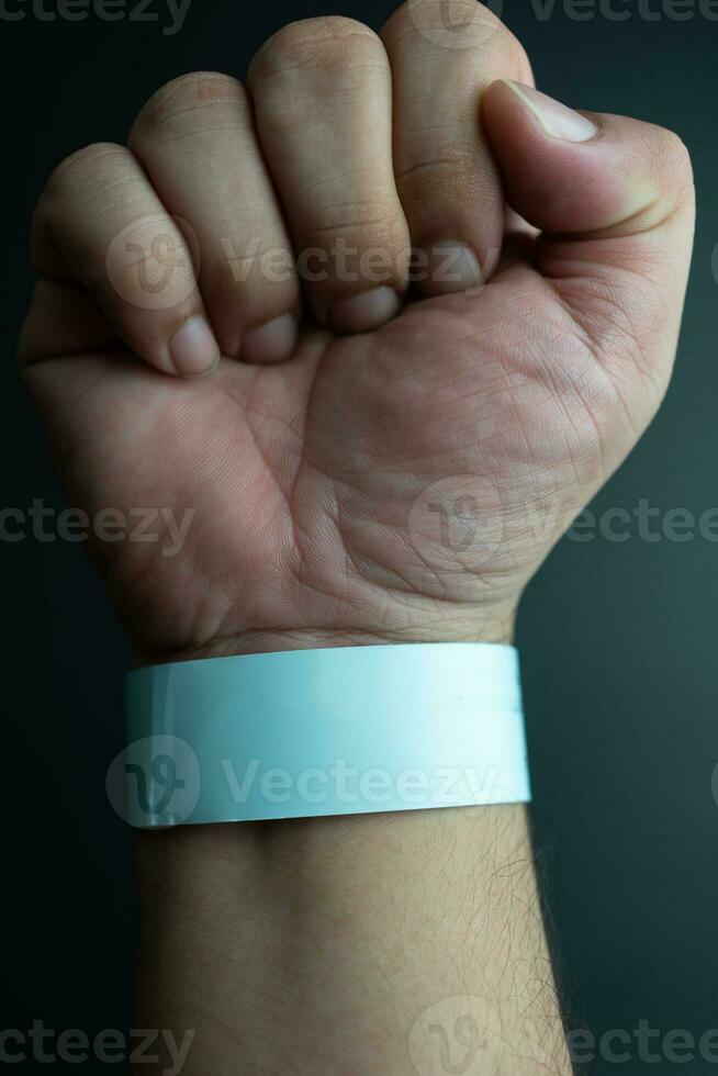 Blue paper wristband mockup on persons arm. Empty adhesive bangle wristlet sticker on male hand. photo