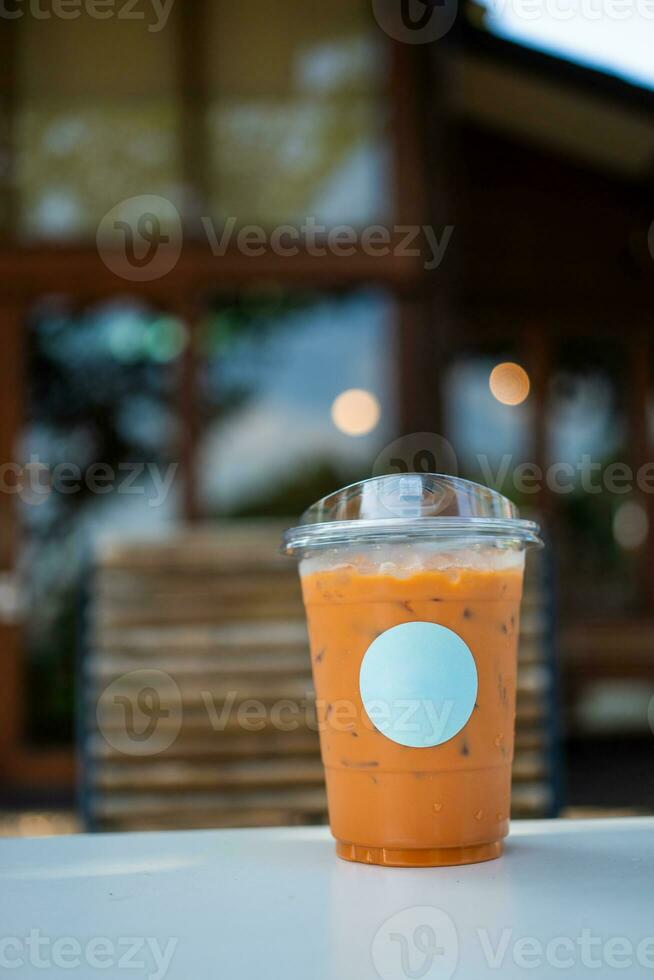 Ice Thai milk tea in a transparent plastic glass with empty white logo. photo