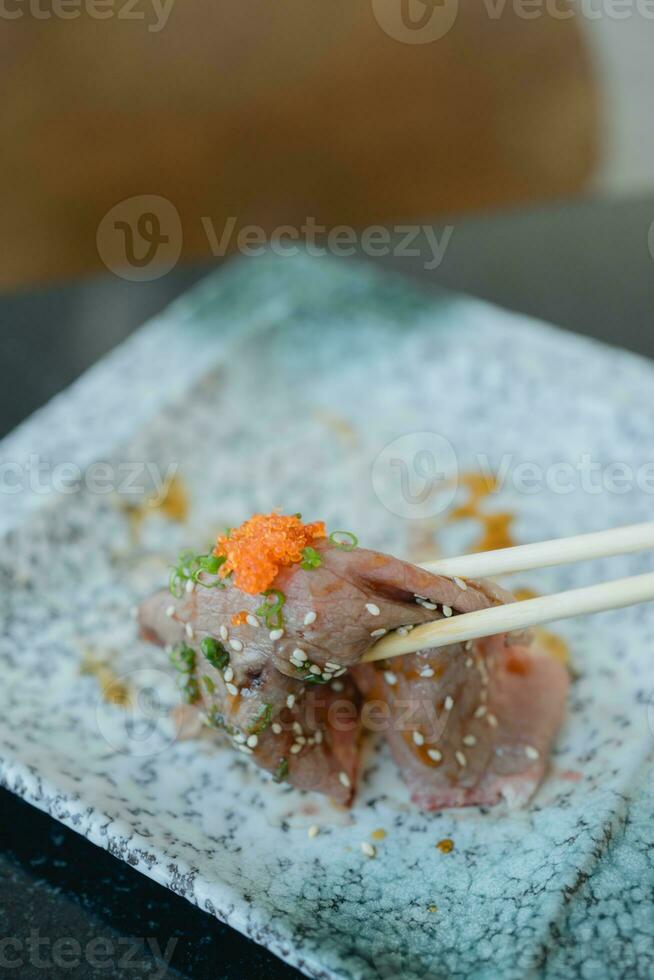 Use chopsticks eating best grade Japanese wagyu beef sushi. photo