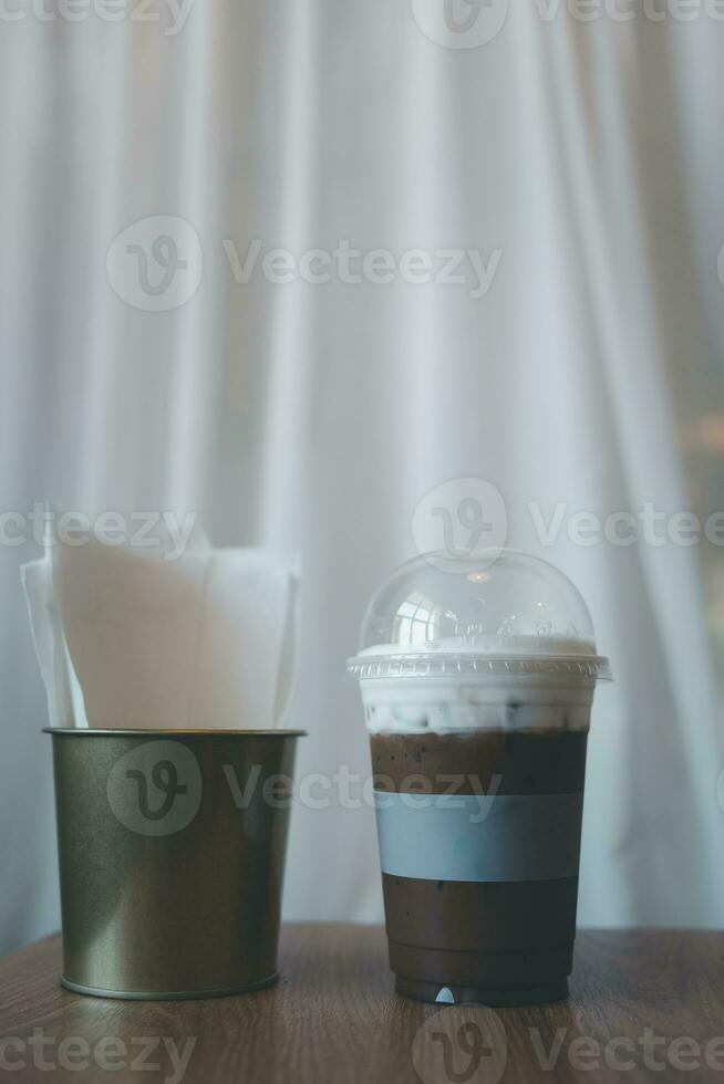 Close up plastic glass of iced mocha coffee topped with soft milk froth photo