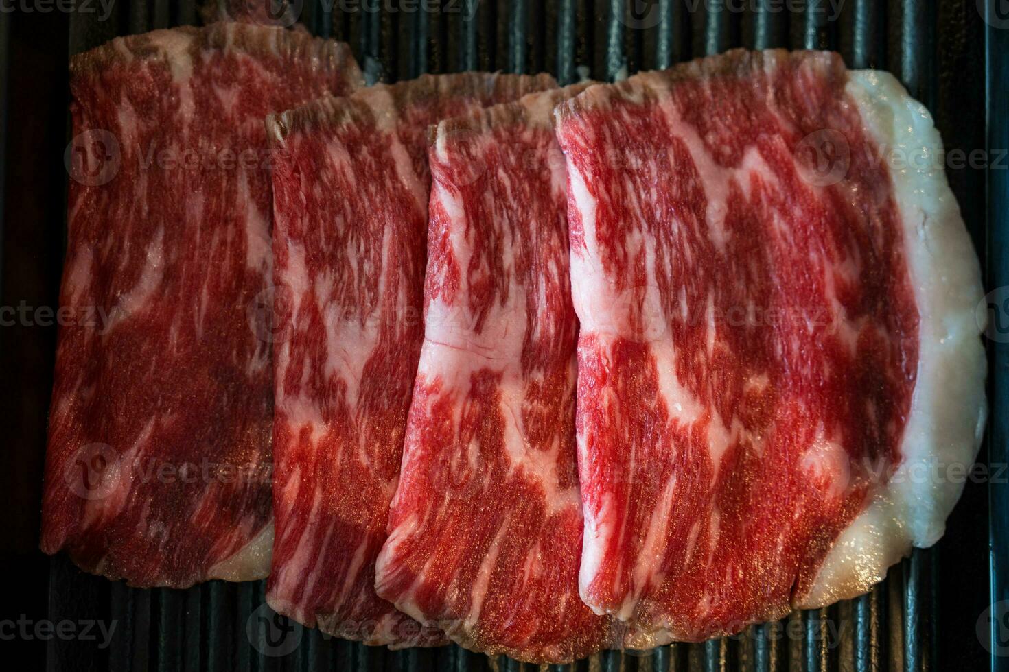 Premium rare slices of beef with high marbled texture on a black tray plate served for hot pots and Shabu. photo