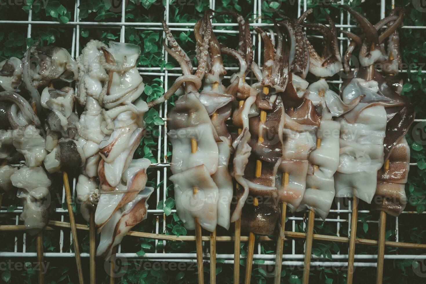 Thai style squid skewers before grill on the tray waiting for customers to buy. photo