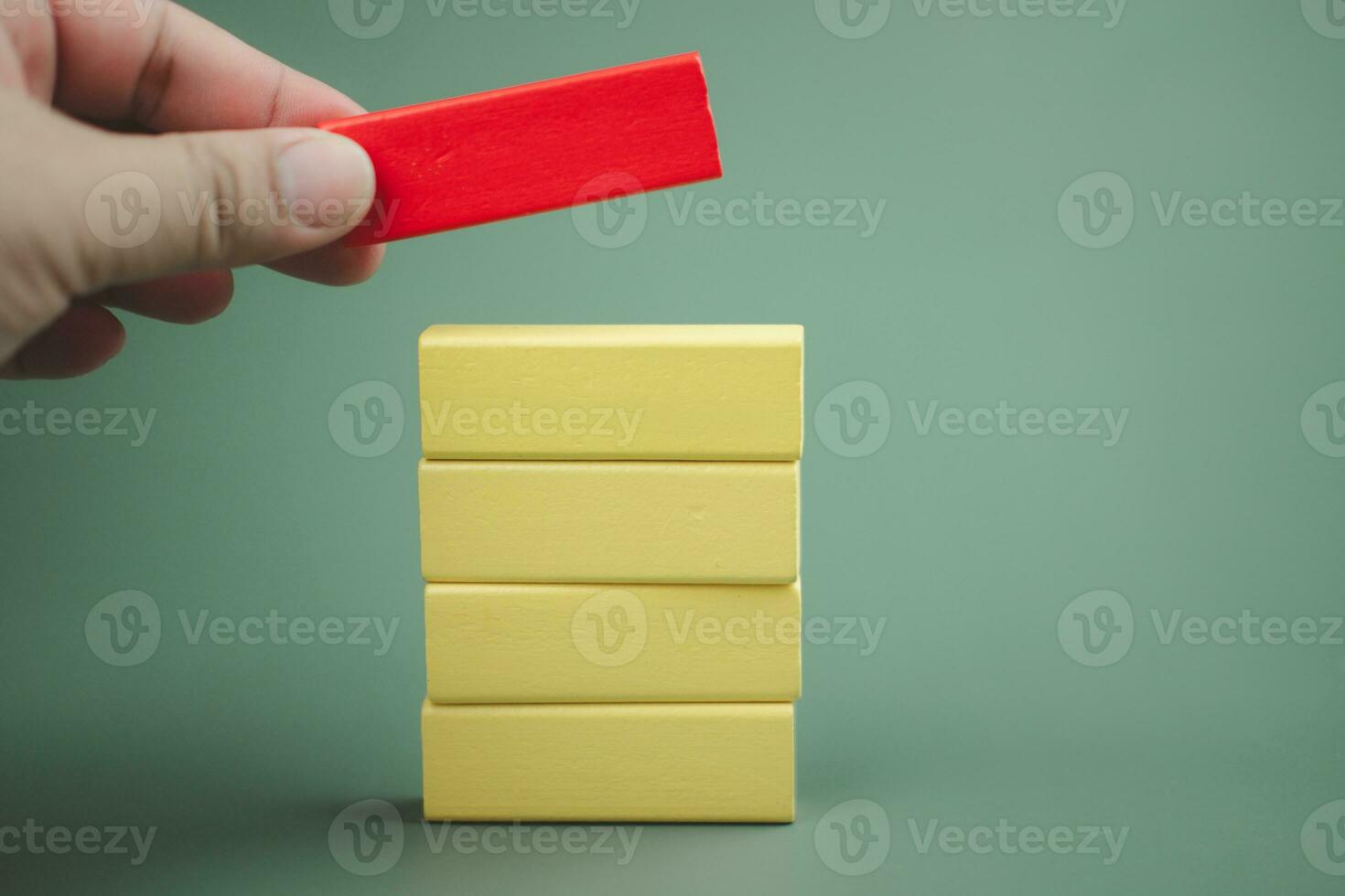Hand putting red wooden block on top of other yellow wooden blocks. Customizable space for text. photo