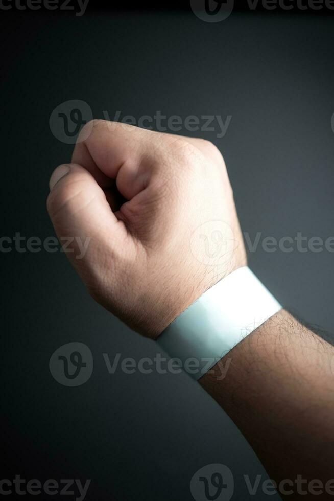Blue paper wristband mockup on persons arm. Empty adhesive bangle wristlet sticker on male hand. photo