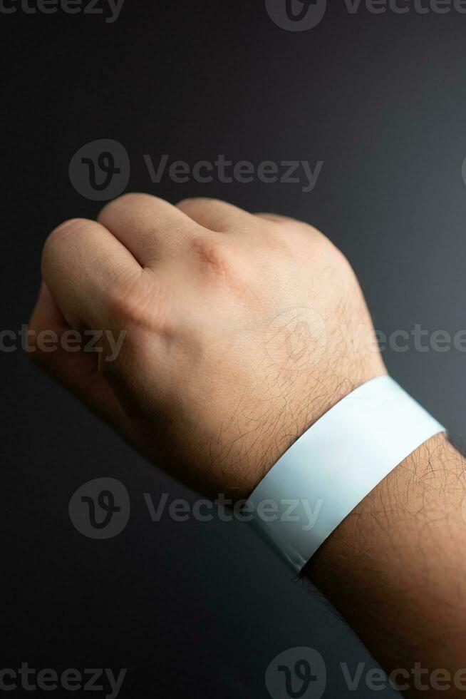 Blue paper wristband mockup on persons arm. Empty adhesive bangle wristlet sticker on male hand. photo