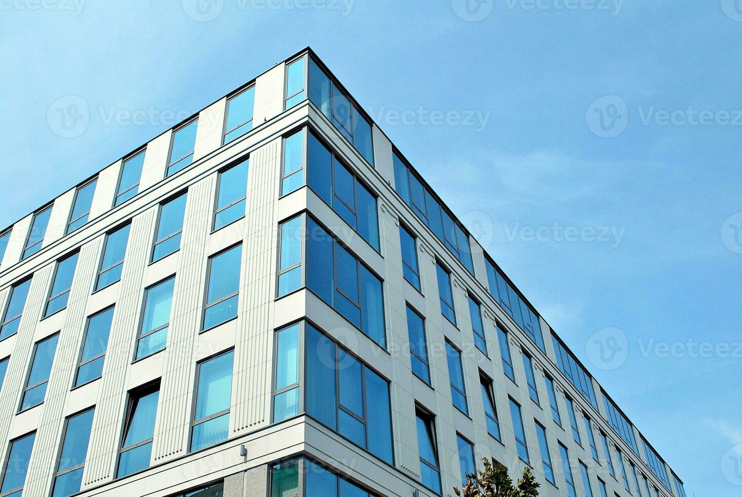 Abstract closeup of the glass-clad facade of a modern building covered in reflective plate glass. Architecture abstract background. Glass wall and facade detail. photo