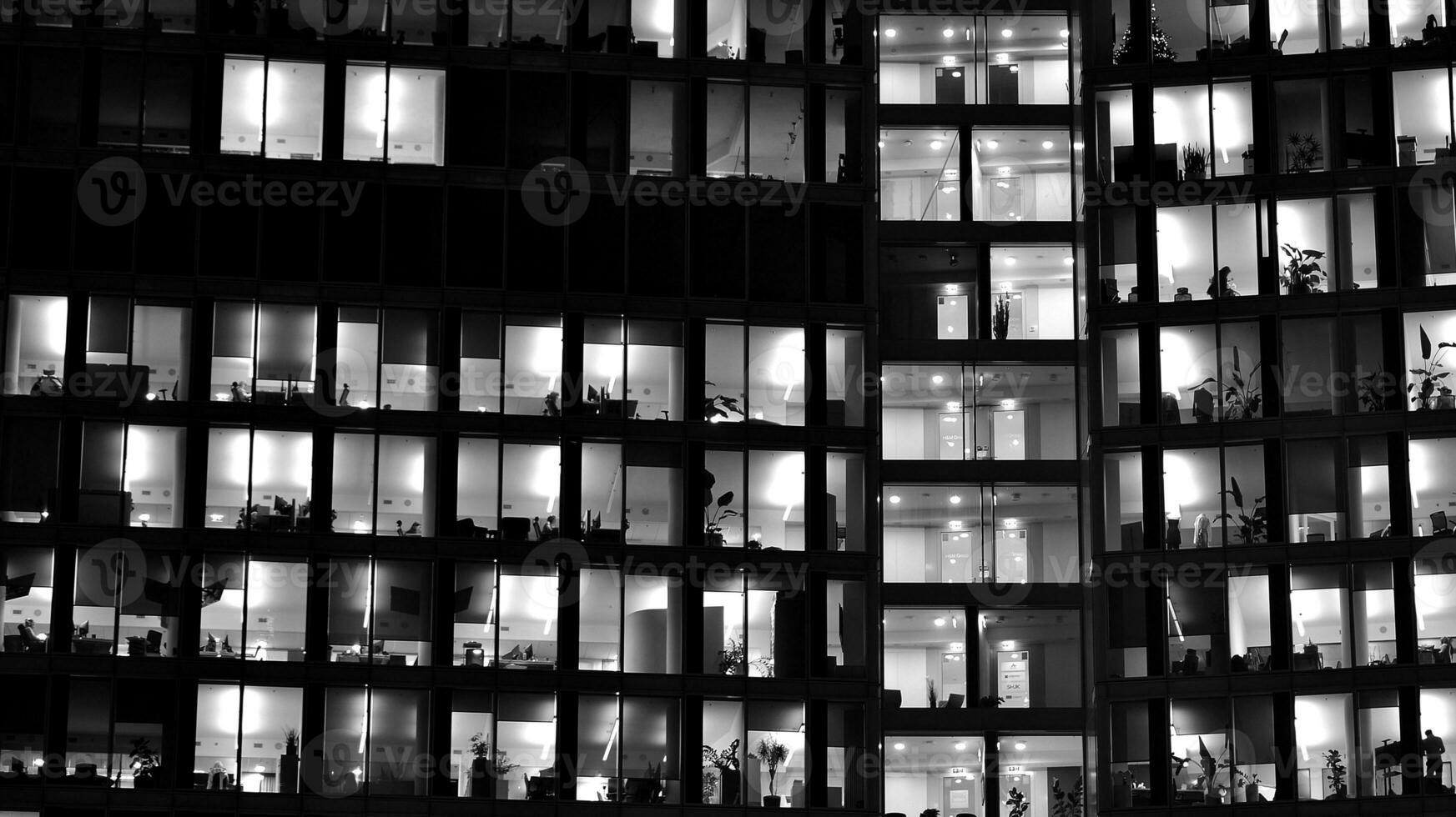 Pattern of office buildings windows illuminated at night. Glass architecture ,corporate building at night - business concept. Black and white. photo