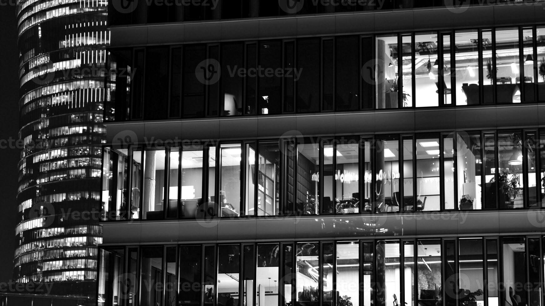 Pattern of office buildings windows illuminated at night. Glass architecture ,corporate building at night - business concept. Black and white. photo