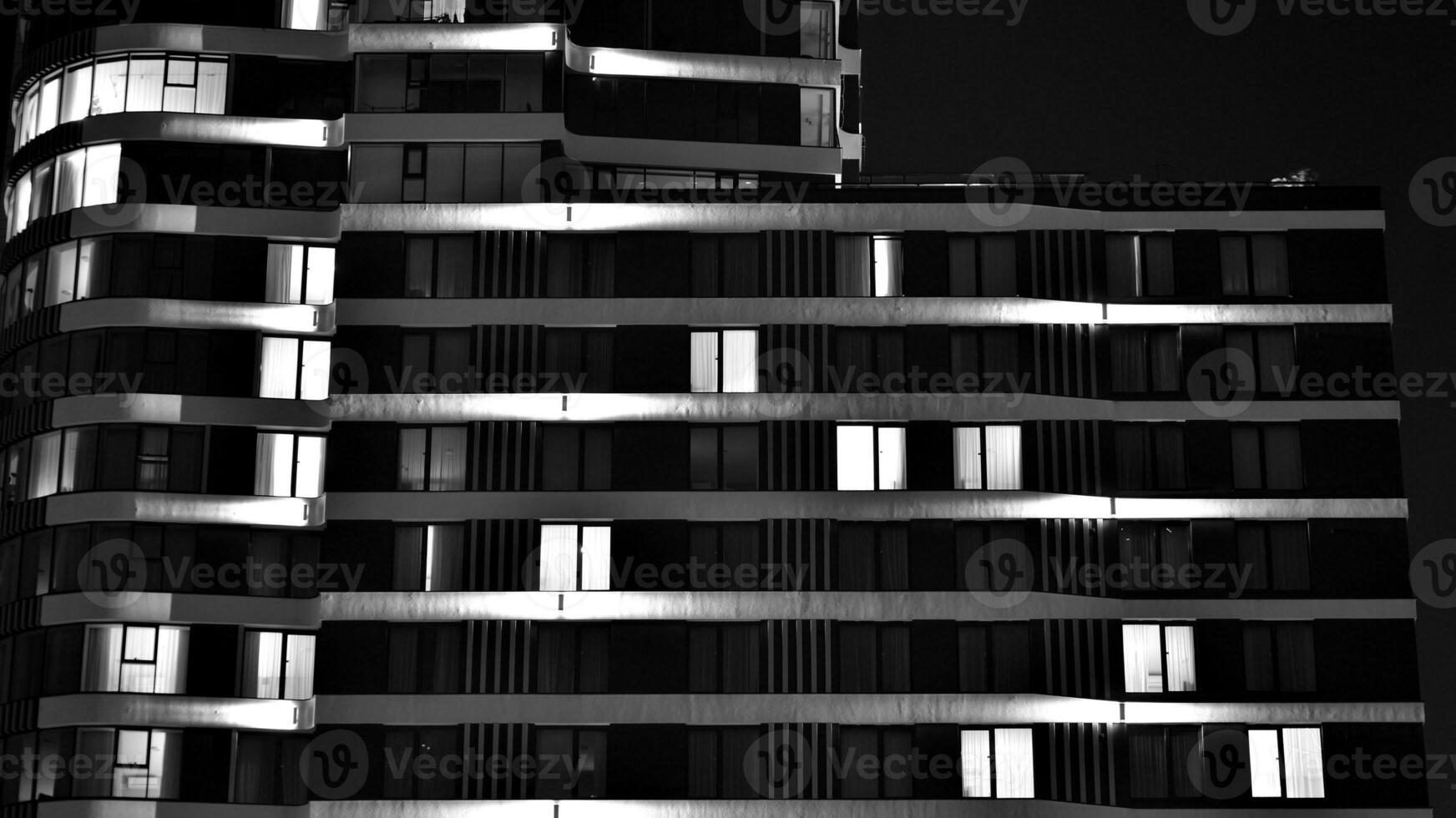 Pattern of office buildings windows illuminated at night. Glass architecture ,corporate building at night - business concept. Black and white. photo