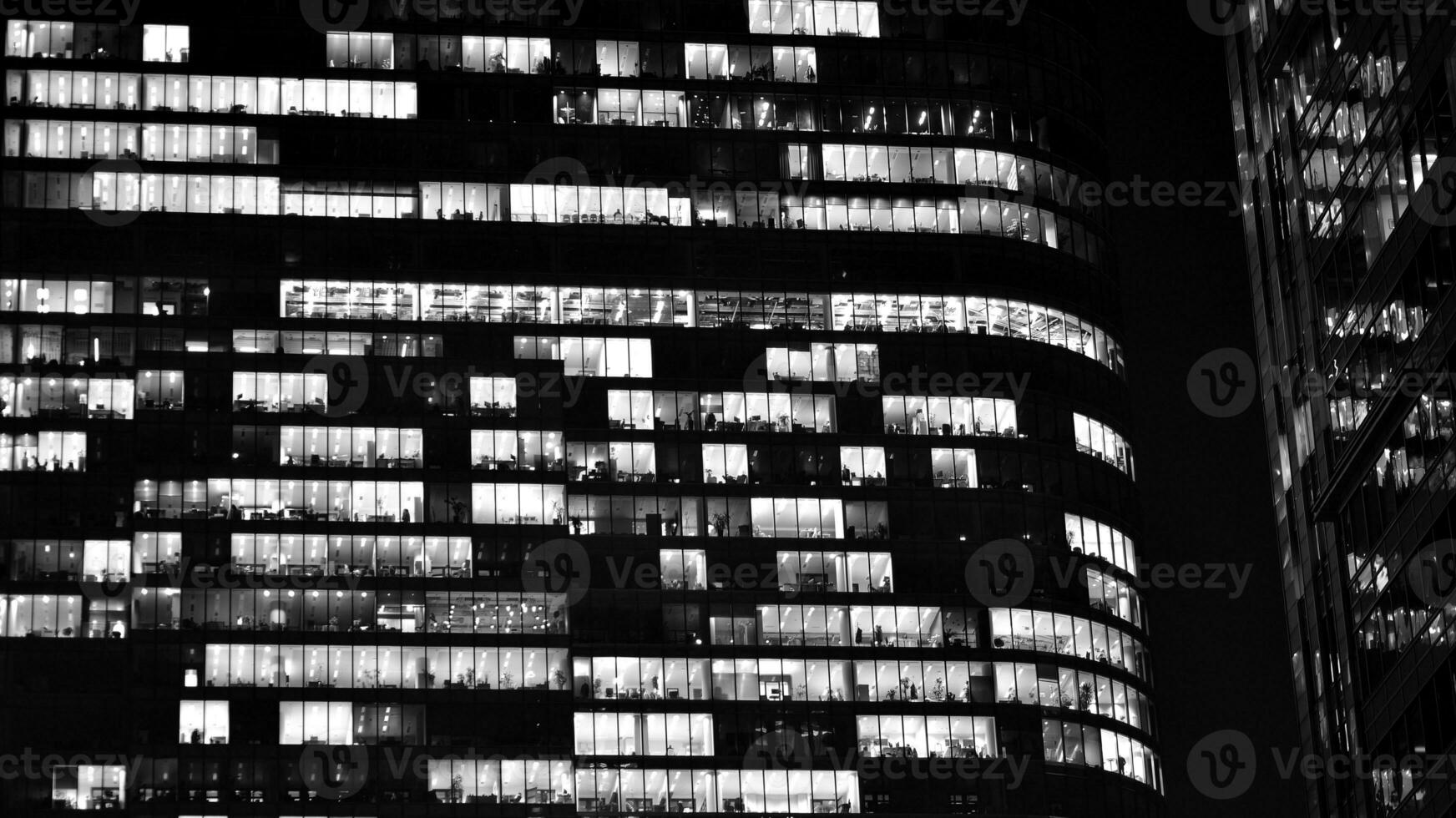 Pattern of office buildings windows illuminated at night. Glass architecture ,corporate building at night - business concept. Black and white. photo