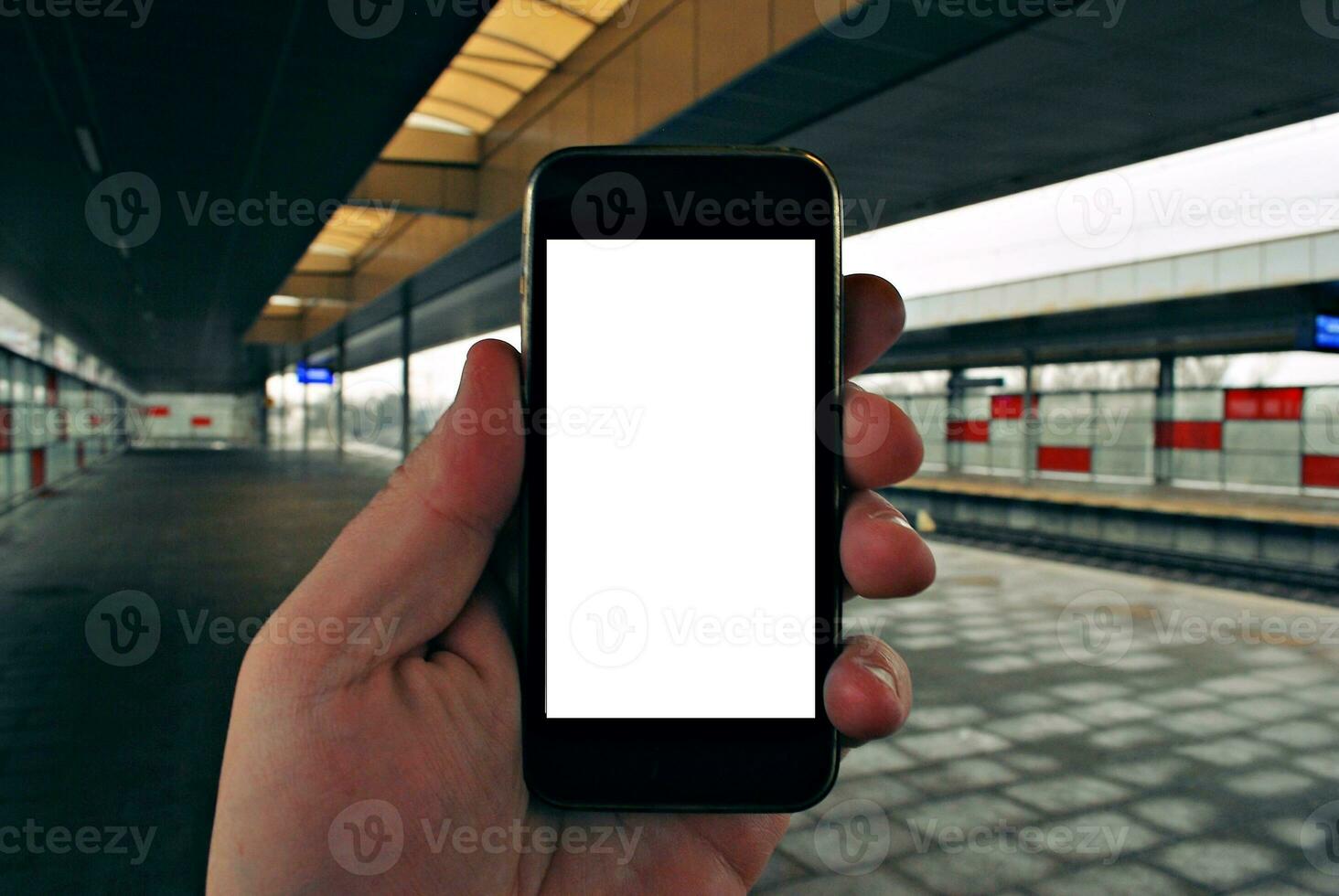 Hand holding smartphone with subway station background photo