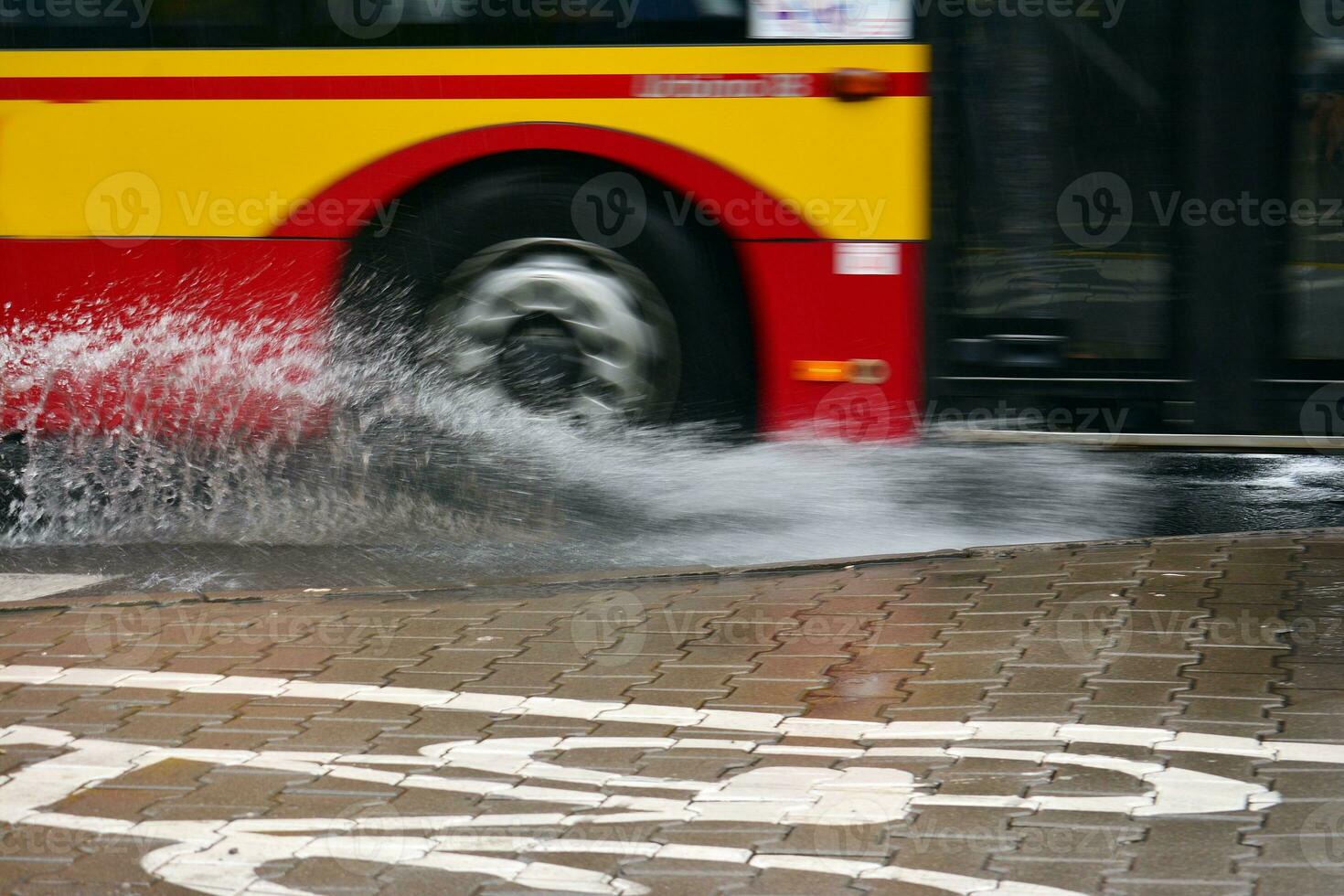 Splashes from under the wheels of the bus during heavy rain. Blurred bus. photo