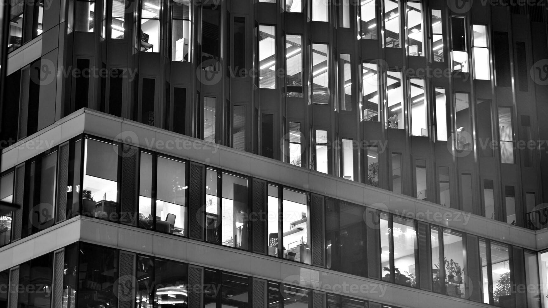 Pattern of office buildings windows illuminated at night. Glass architecture ,corporate building at night - business concept. Black and white. photo