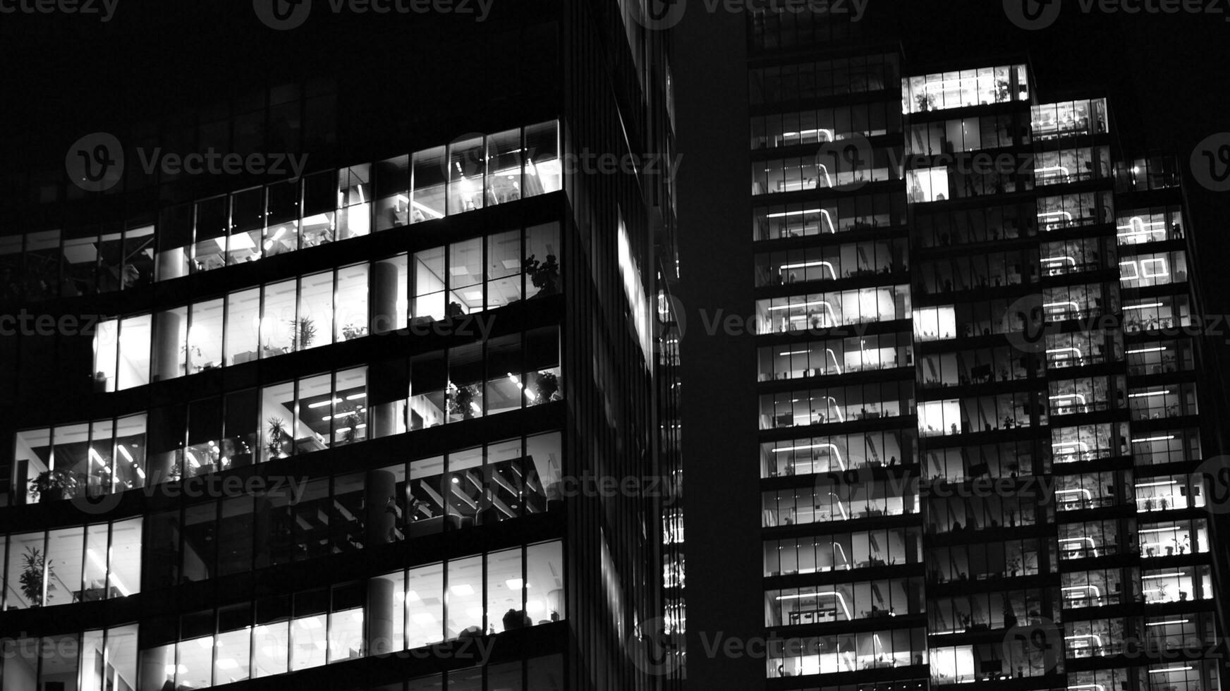 Pattern of office buildings windows illuminated at night. Glass architecture ,corporate building at night - business concept. Black and white. photo