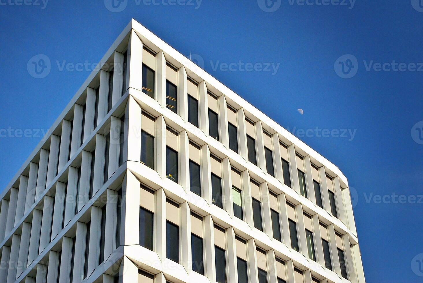 Abstract closeup of the glass-clad facade of a modern building covered in reflective plate glass. Architecture abstract background. Glass wall and facade detail. photo