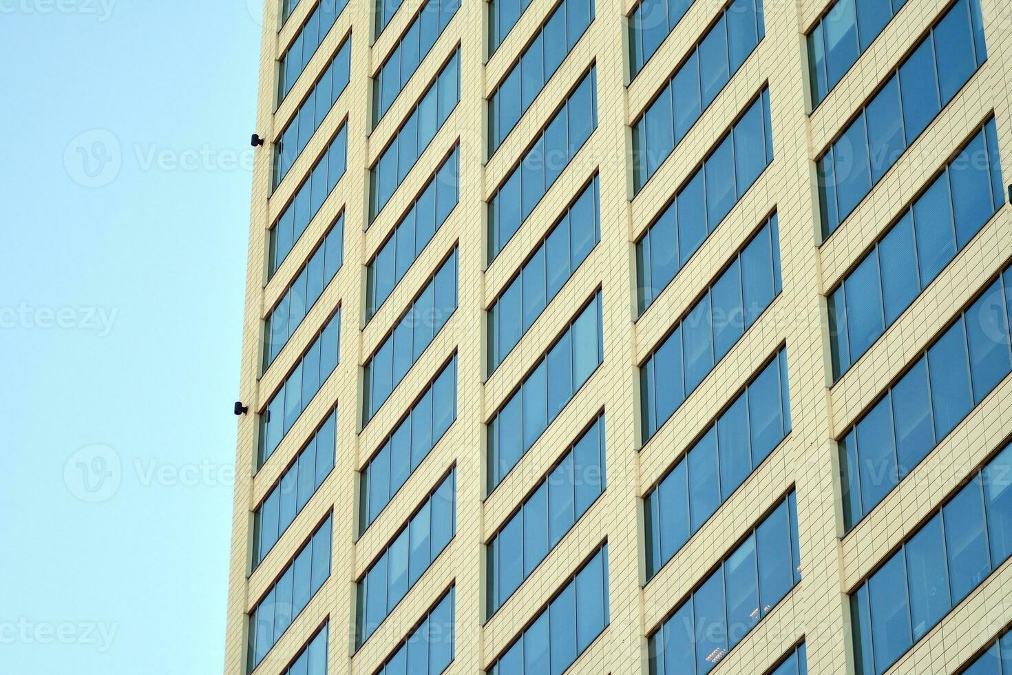 Glass building with transparent facade of the building and blue sky. Structural glass wall reflecting blue sky. Abstract modern architecture fragment. Contemporary architectural background. photo