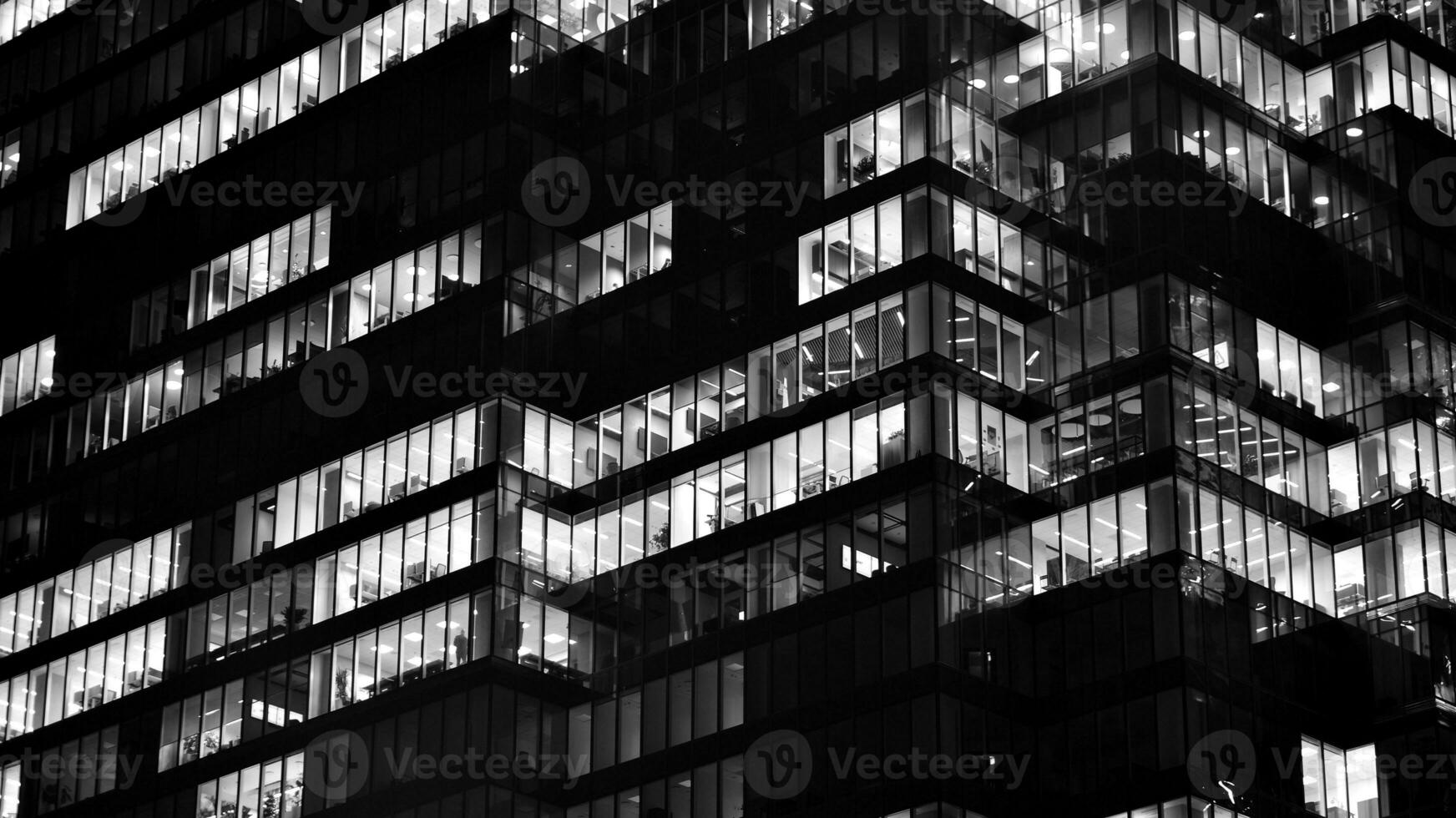 Pattern of office buildings windows illuminated at night. Glass architecture ,corporate building at night - business concept. Black and white. photo