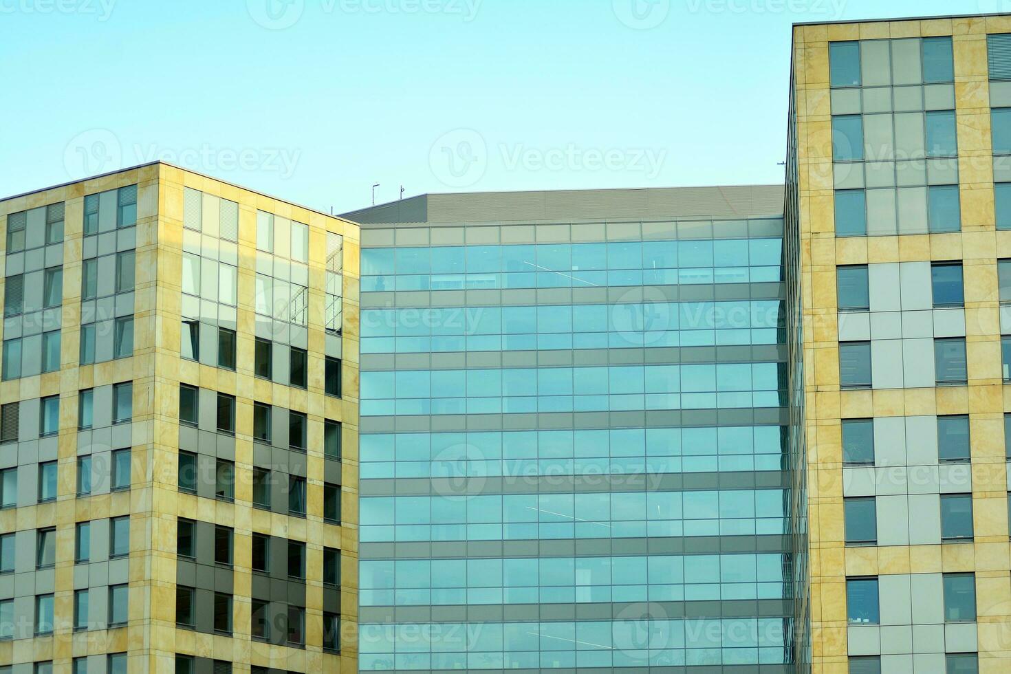 Abstract closeup of the glass-clad facade of a modern building covered in reflective plate glass. Architecture abstract background. Glass wall and facade detail. photo