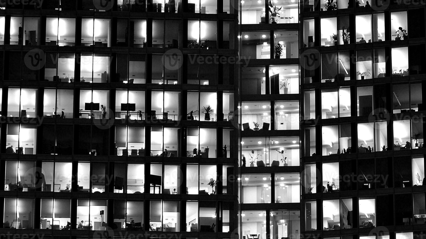 Pattern of office buildings windows illuminated at night. Glass architecture ,corporate building at night - business concept. Black and white. photo