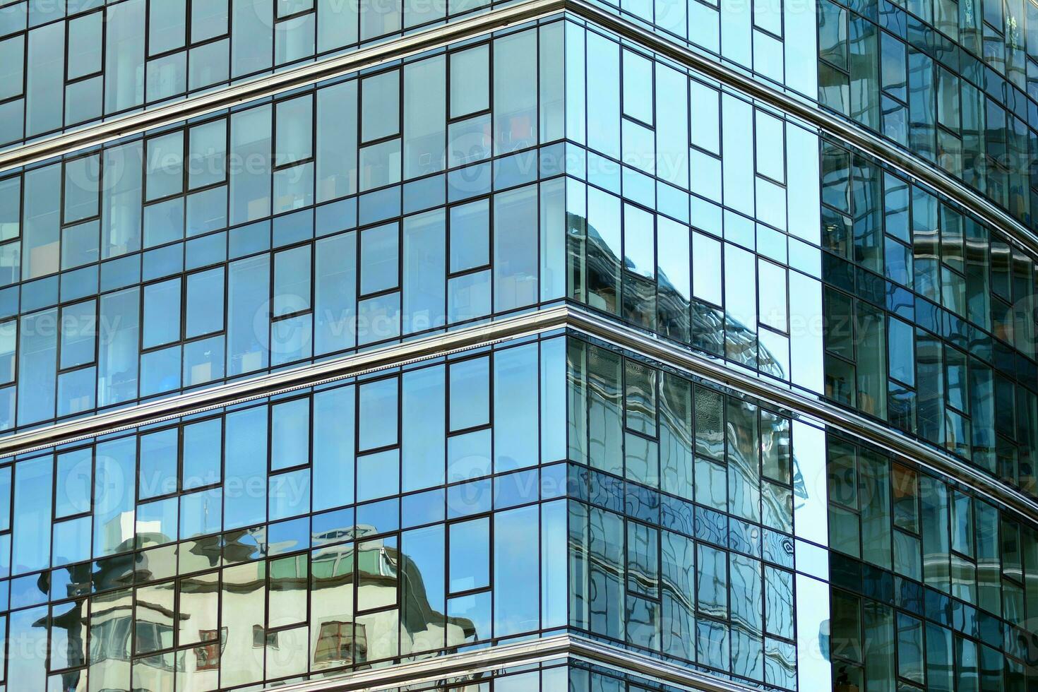 Glass building with transparent facade of the building and blue sky. Structural glass wall reflecting blue sky. Abstract modern architecture fragment. Contemporary architectural background. photo