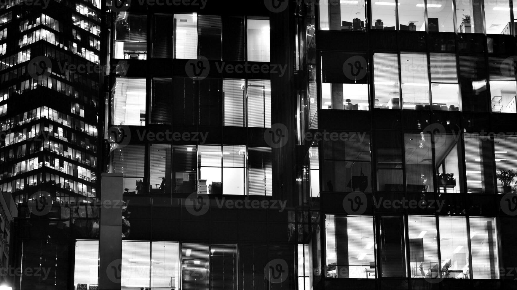 Pattern of office buildings windows illuminated at night. Glass architecture ,corporate building at night - business concept. Black and white. photo