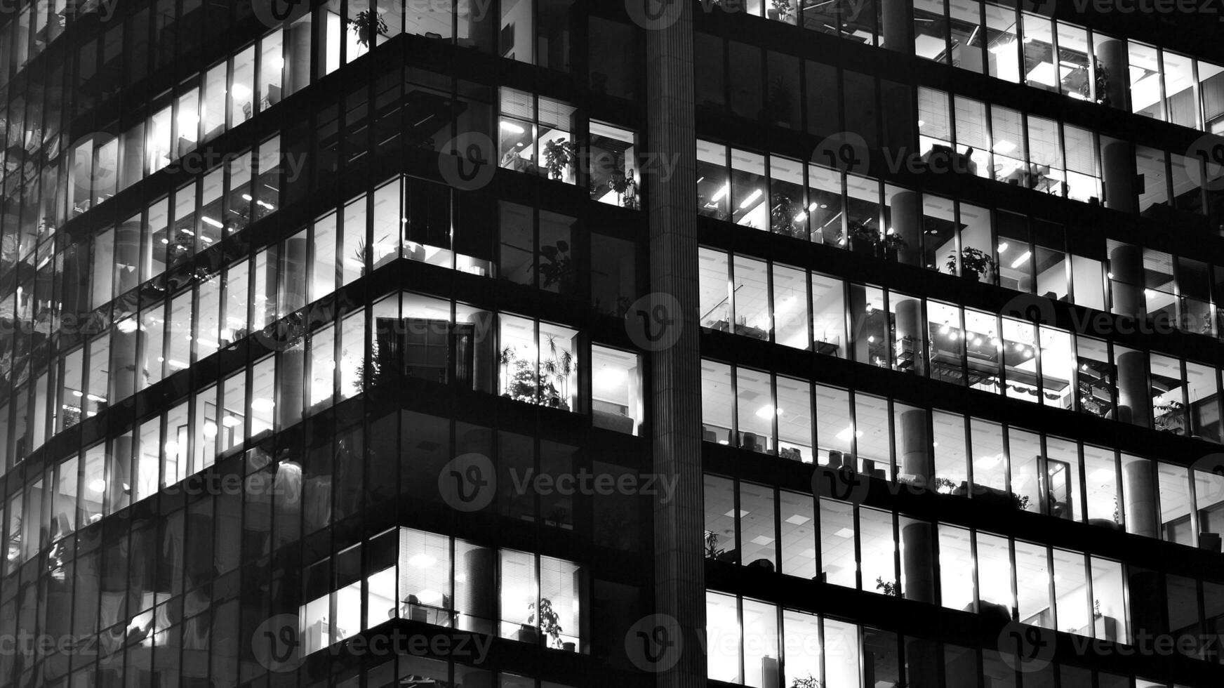 Pattern of office buildings windows illuminated at night. Glass architecture ,corporate building at night - business concept. Black and white. photo