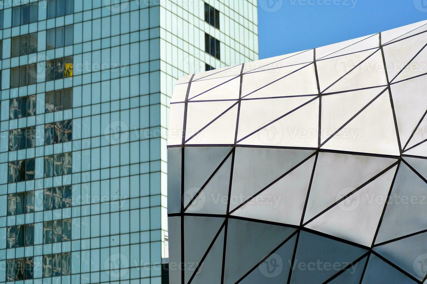 Abstract closeup of the glass-clad facade of a modern building covered in reflective plate glass. Architecture abstract background. Glass wall and facade detail. photo