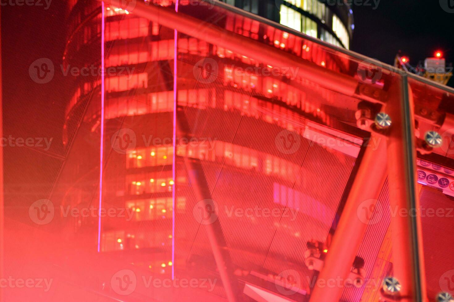 Fragment of the glass facade of a modern corporate building at night. Modern glass office  in city. Big glowing windows in modern office buildings at night, in rows of windows light shines. photo
