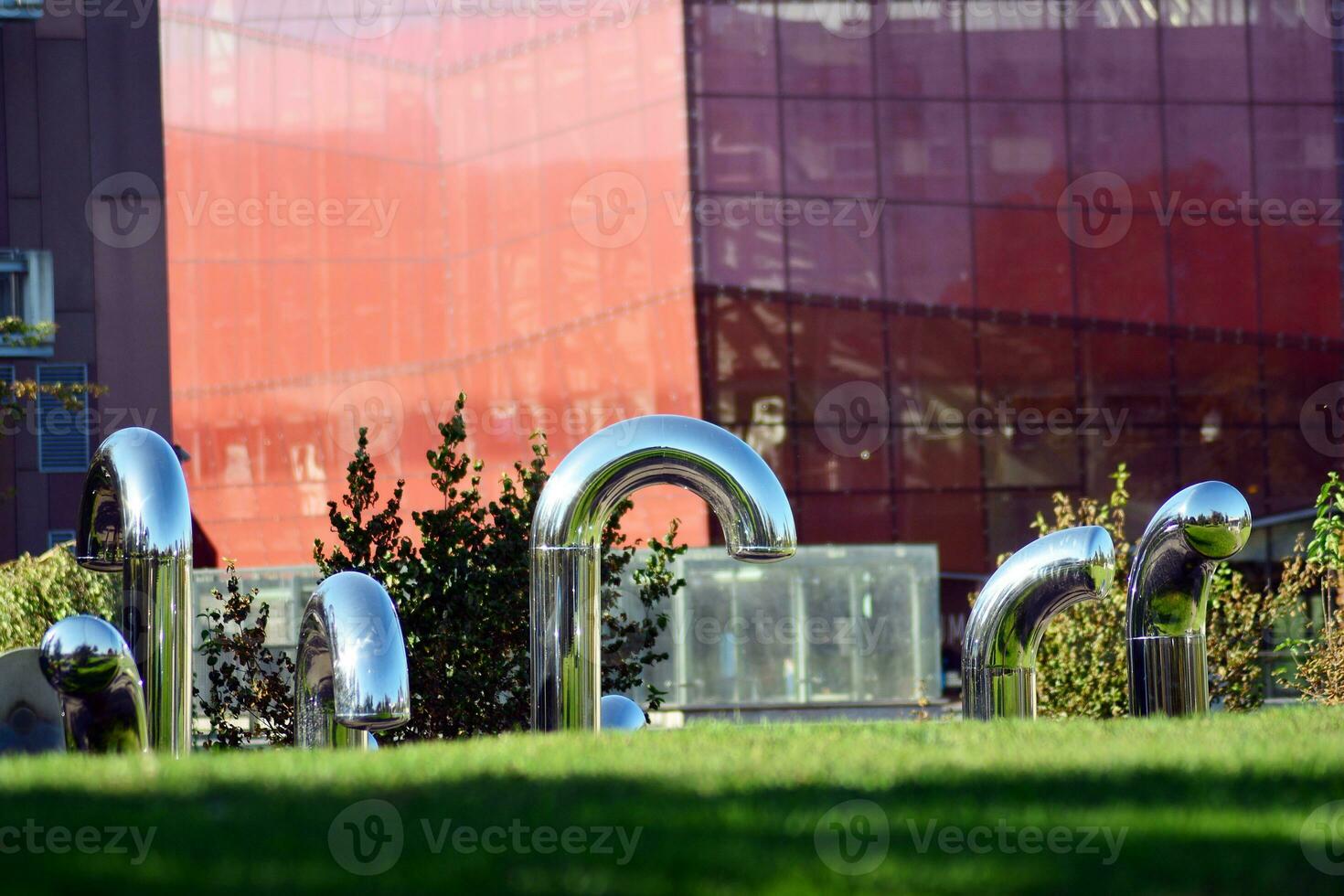 Public art installation in front modern building.Decorative stainless steel pipes photo