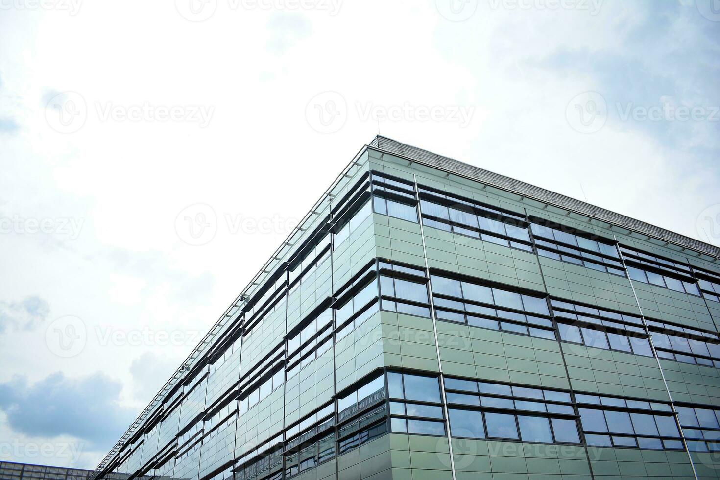 Abstract closeup of the glass-clad facade of a modern building covered in reflective plate glass. Architecture abstract background. Glass wall and facade detail. photo