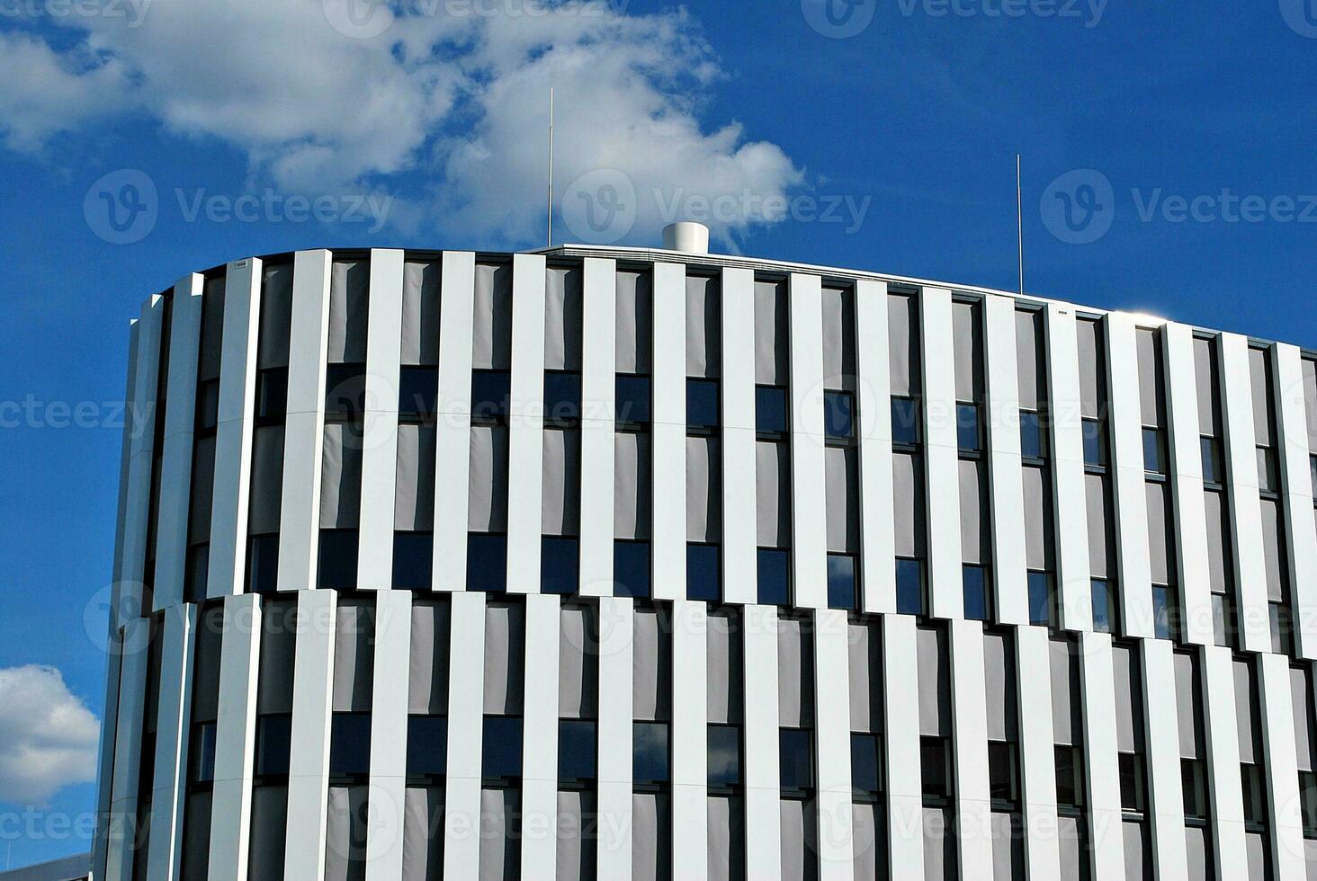 Abstract closeup of the glass-clad facade of a modern building covered in reflective plate glass. Architecture abstract background. Glass wall and facade detail. photo