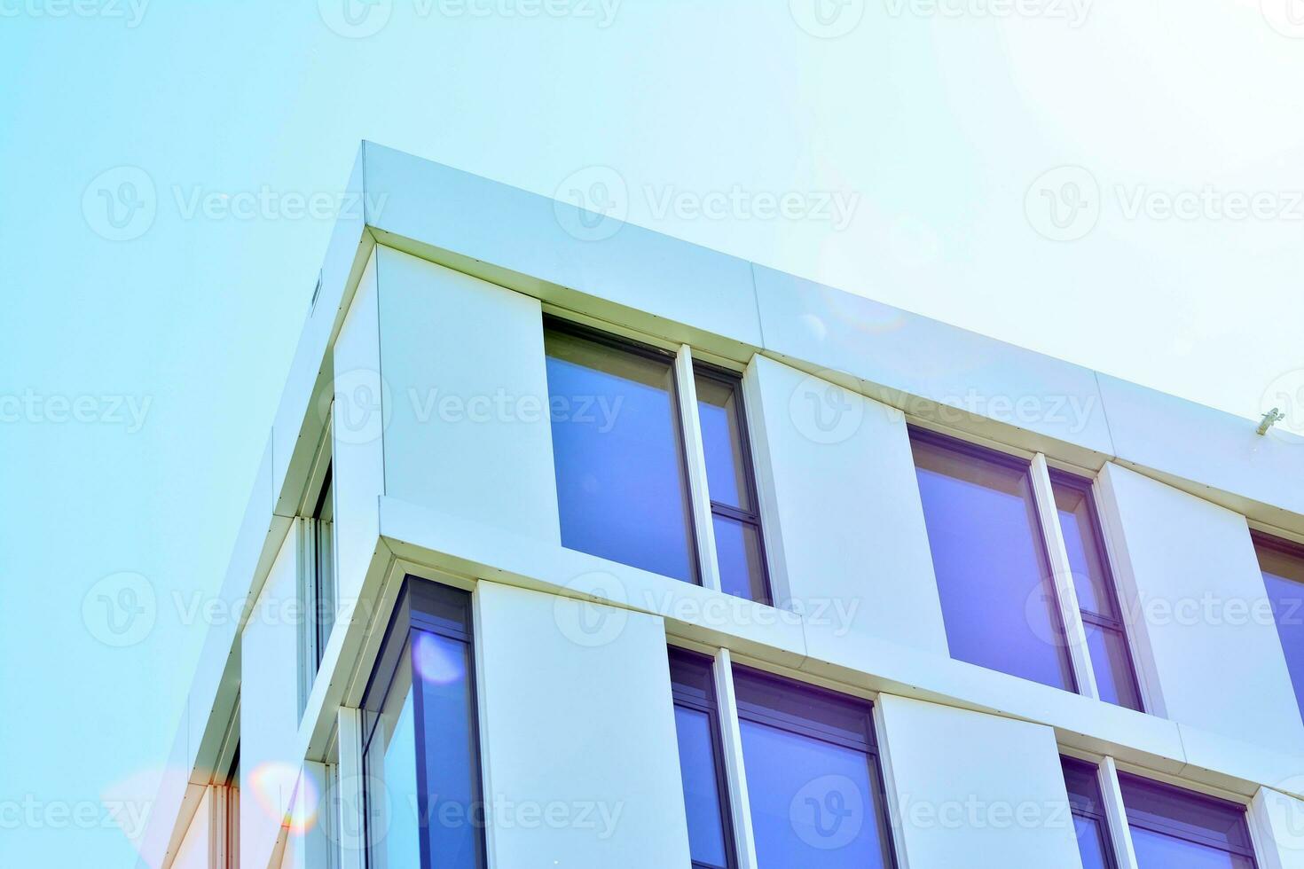 Abstract closeup of the glass-clad facade of a modern building covered in reflective plate glass. Architecture abstract background. Glass wall and facade detail. photo