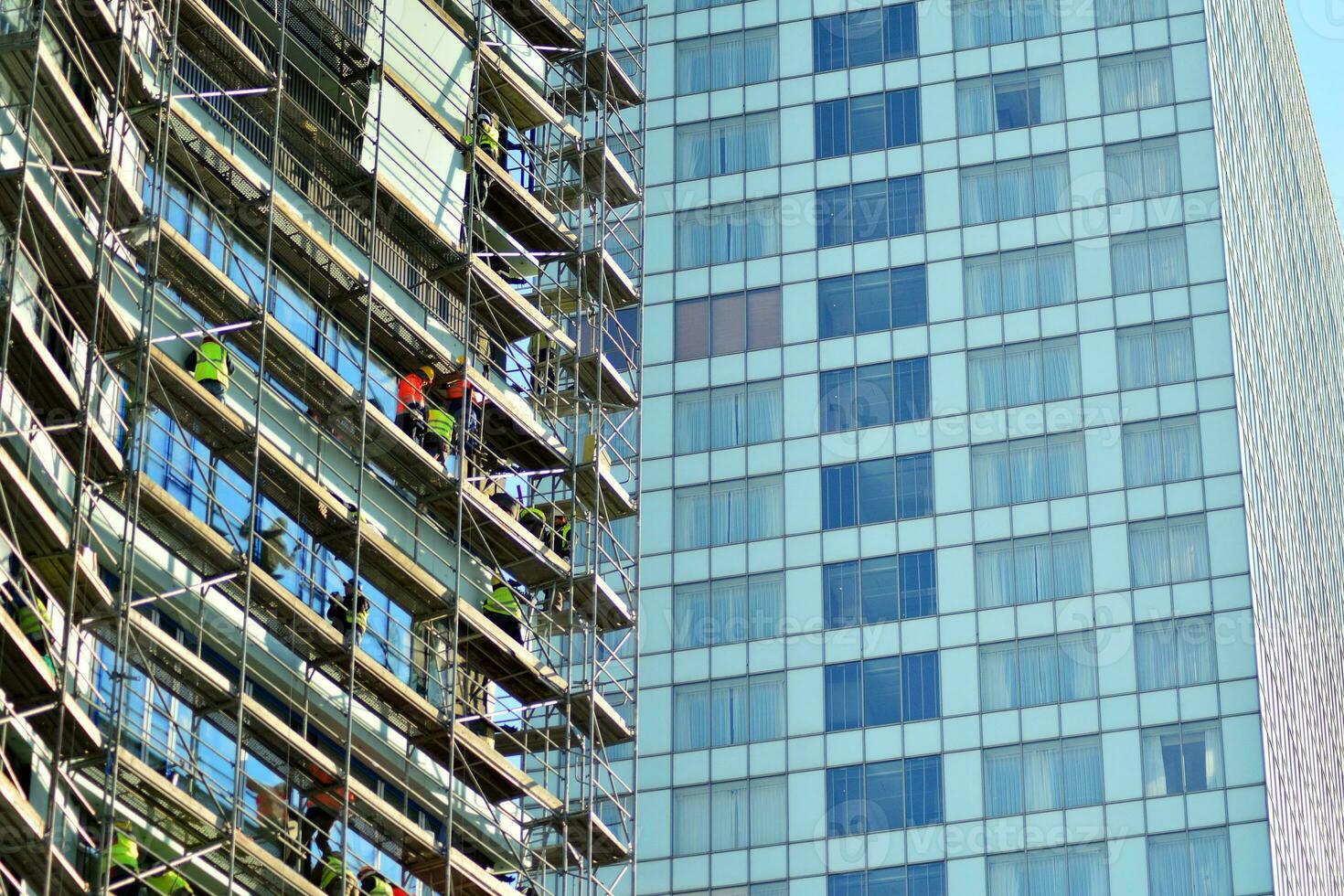 High rise building under construction. Installation of glass facade panels on a reinforced concrete structure. photo