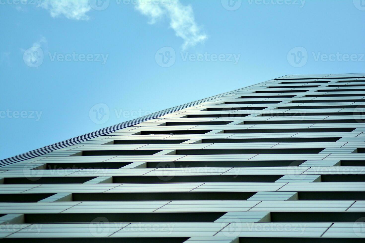 Abstract closeup of the glass-clad facade of a modern building covered in reflective plate glass. Architecture abstract background. Glass wall and facade detail. photo
