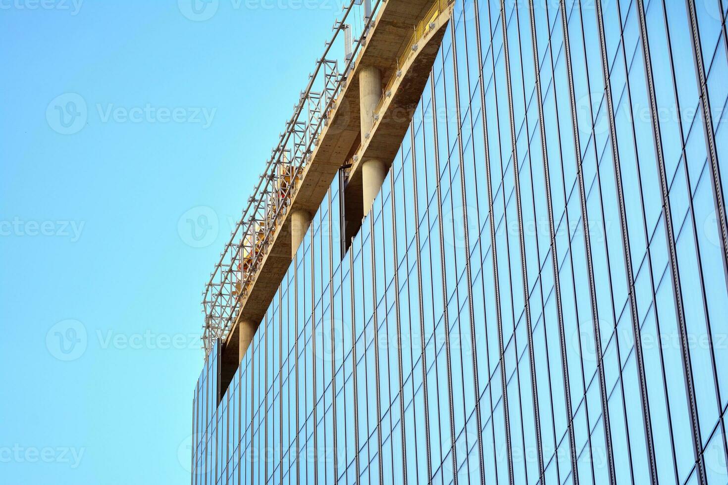 High rise building under construction. Installation of glass facade panels on a reinforced concrete structure. photo