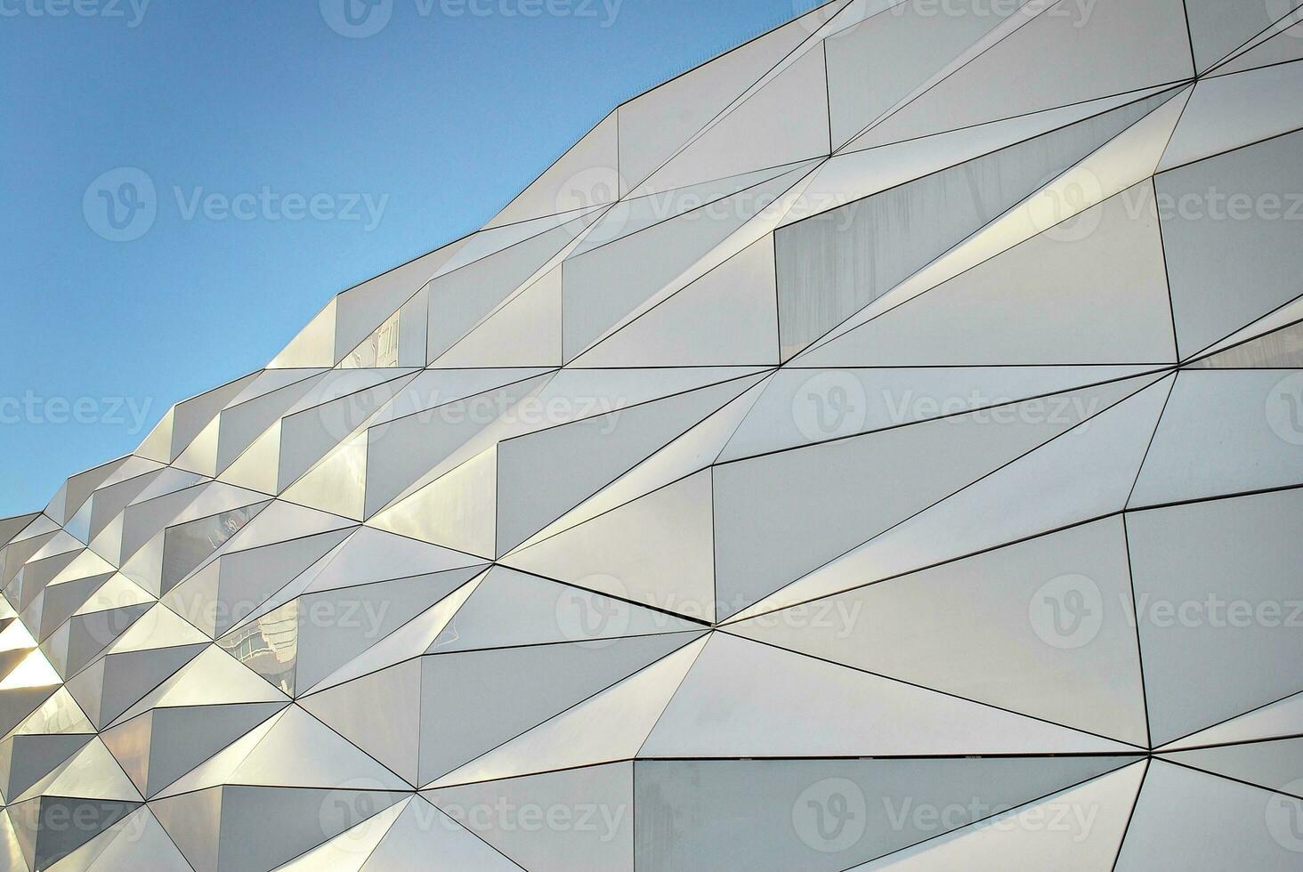 Abstract closeup of the glass-clad facade of a modern building covered in reflective plate glass. Architecture abstract background. Glass wall and facade detail. photo