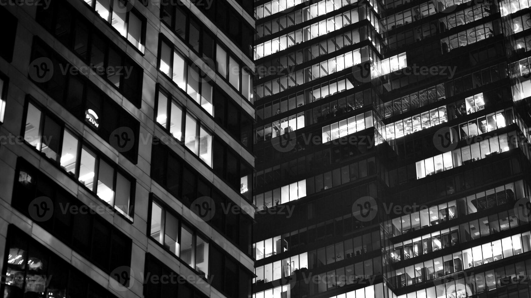 Pattern of office buildings windows illuminated at night. Glass architecture ,corporate building at night - business concept. Black and white. photo