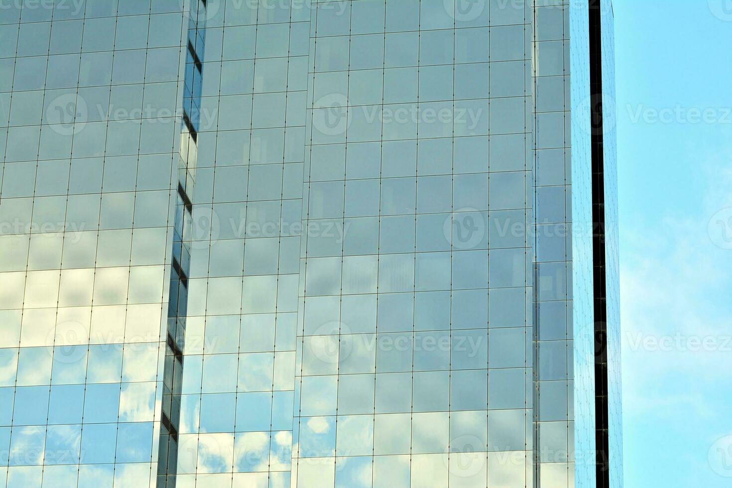 Glass building with transparent facade of the building and blue sky. Structural glass wall reflecting blue sky. Abstract modern architecture fragment. Contemporary architectural background. photo