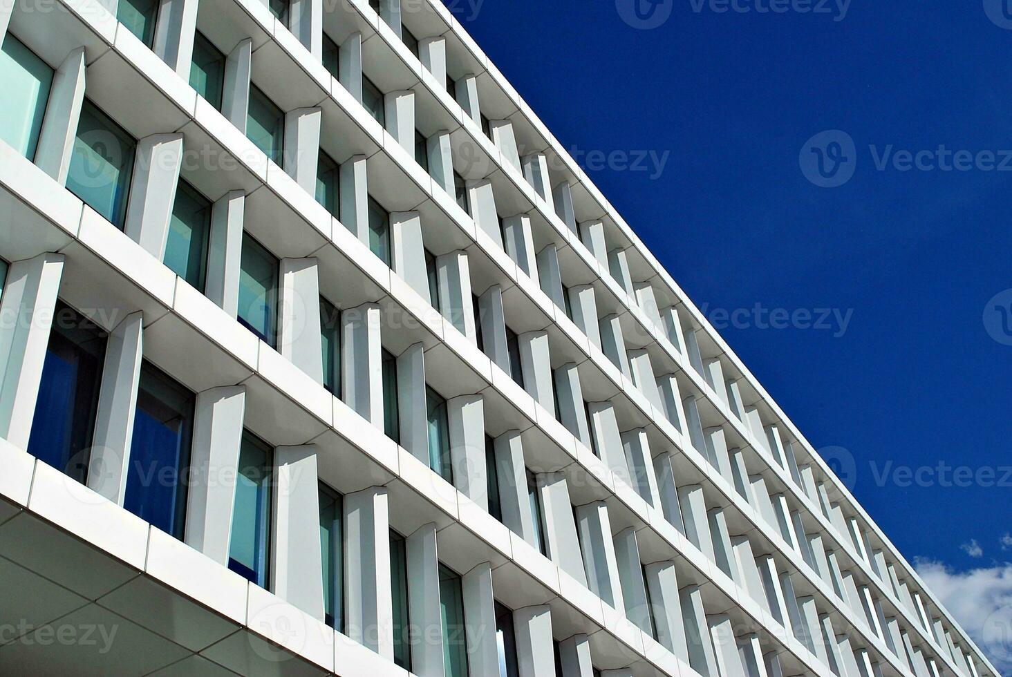 Abstract closeup of the glass-clad facade of a modern building covered in reflective plate glass. Architecture abstract background. Glass wall and facade detail. photo