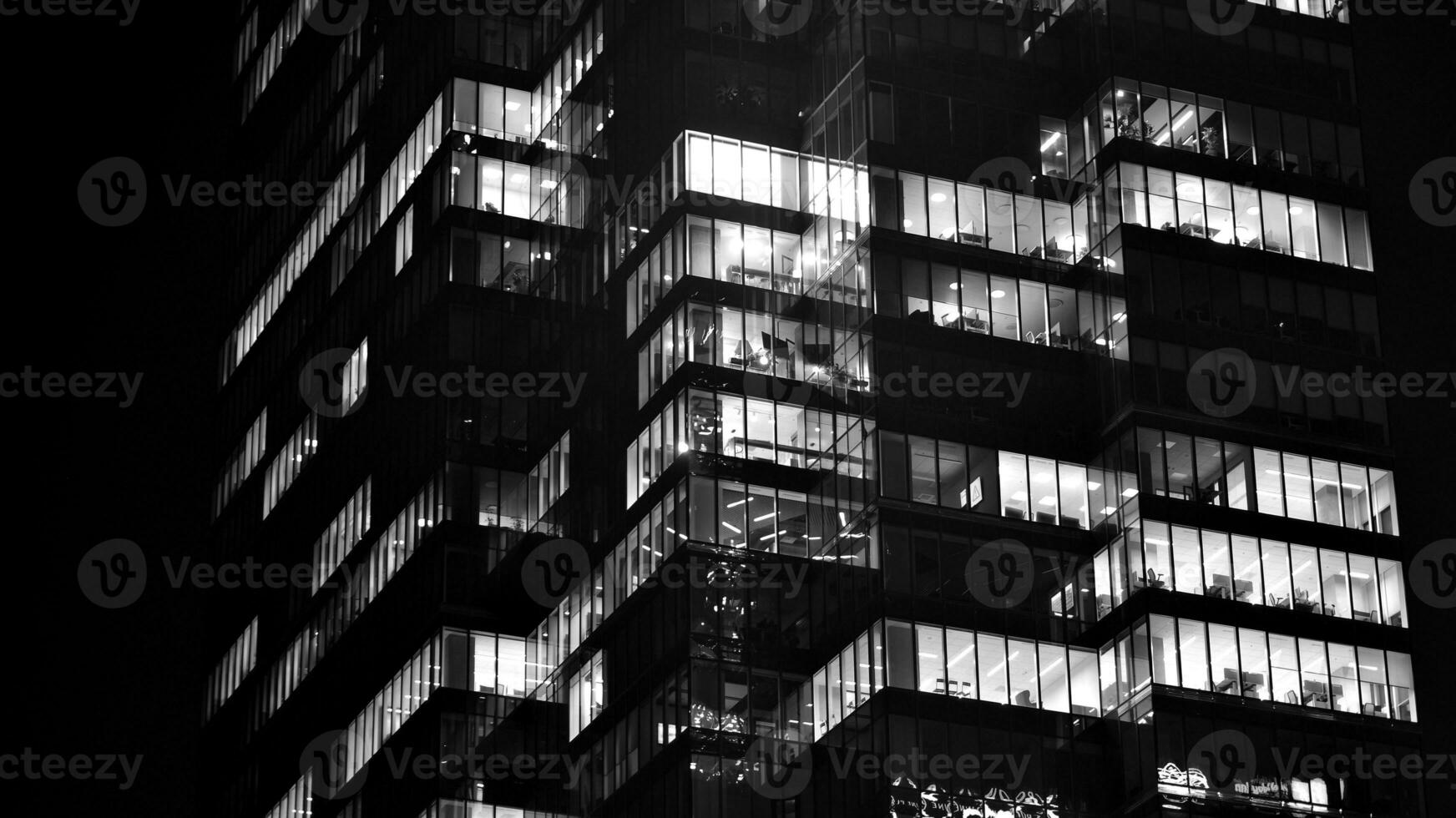 Pattern of office buildings windows illuminated at night. Glass architecture ,corporate building at night - business concept. Black and white. photo