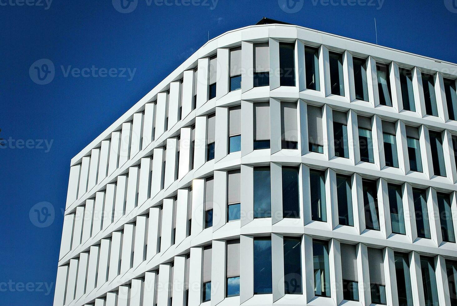 Abstract closeup of the glass-clad facade of a modern building covered in reflective plate glass. Architecture abstract background. Glass wall and facade detail. photo