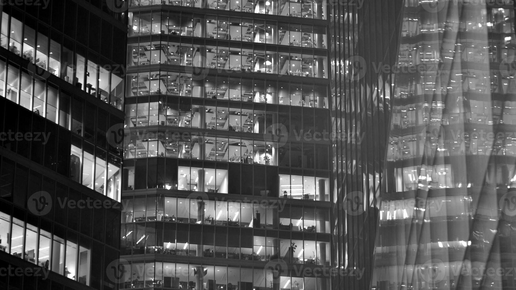 Pattern of office buildings windows illuminated at night. Glass architecture ,corporate building at night - business concept. Black and white. photo