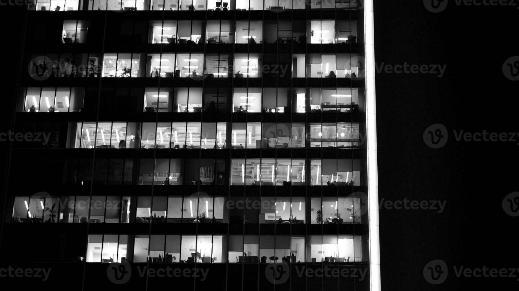 Pattern of office buildings windows illuminated at night. Glass architecture ,corporate building at night - business concept. Black and white. photo